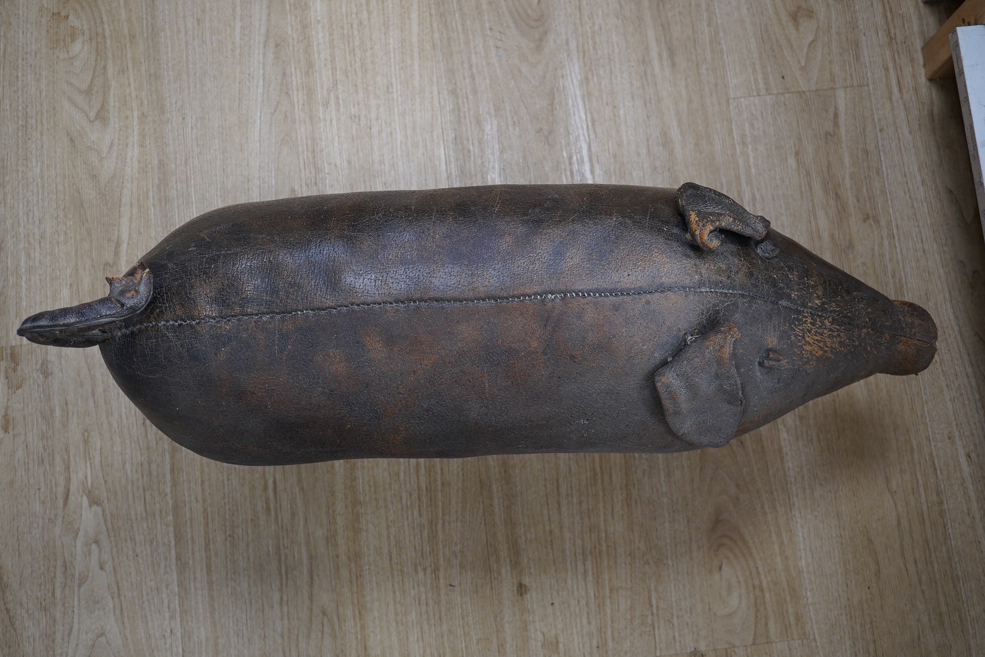 A Liberty brown leather pig foot stool, 90cm long. Condition - the end of the tail and snout are missing and generally leather scuffed